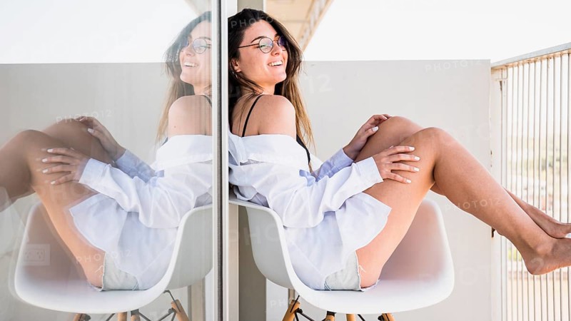 Smiling young woman sitting white chair balcony