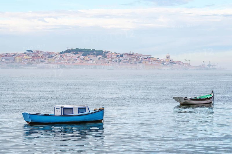 Fishing boats in Tagus river on misty morning with Lisbon in background with miSt Lisbon