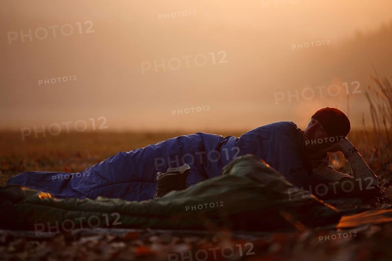 Man lying in a sleeping bag in frosty weather