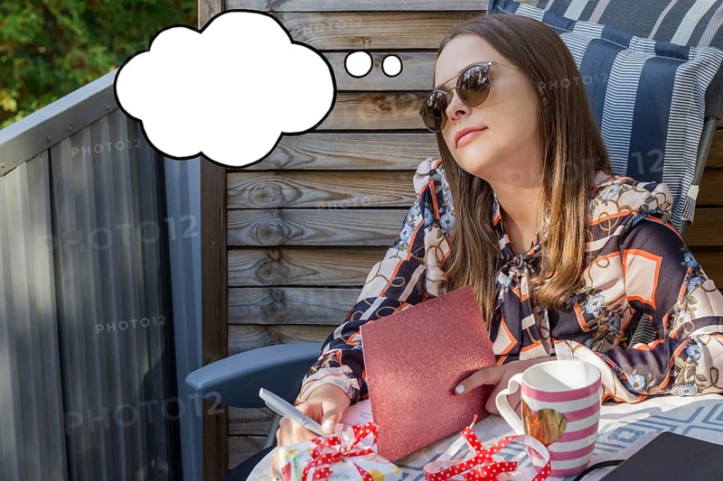 Beautiful young caucasian woman thinking about something while writing a greeting card. Image with thinking bubble. Birthday