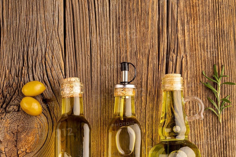 Yellow olives oil bottles wooden background