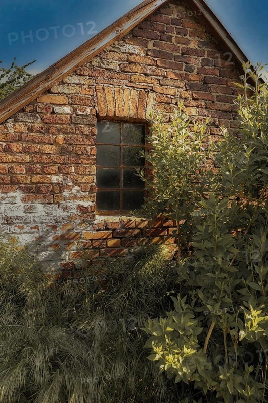 Old brick house with mullioned window in the sunlight