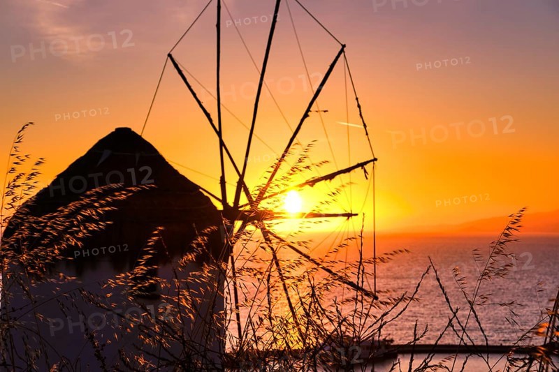 Silhouette of famous traditional Greek windmill against colorful sunset sky