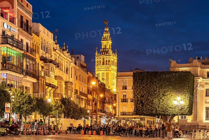 Restaurants in the Plaza de San Francisco and the Giralda bell tower of Santa Maria de la Sede Cathedral at dusk