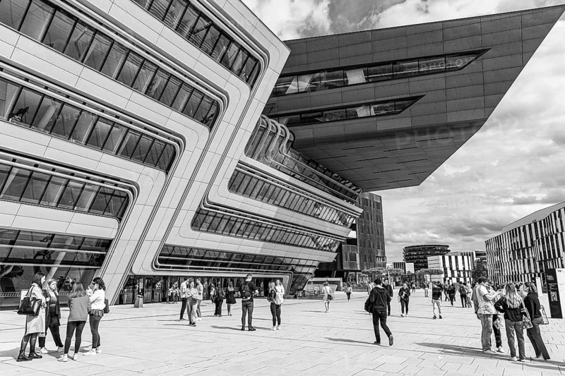Students in front of a modern building on the campus of the University of Economics WU