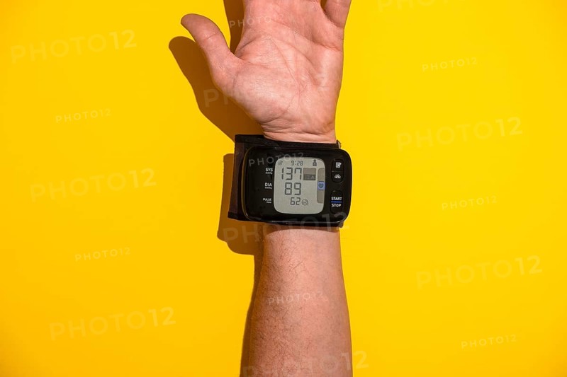 Blood pressure monitor on a man's trading joint against a yellow background