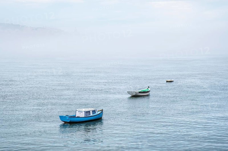 Boats in river on misty morning with background with heavy fog. Lisbon