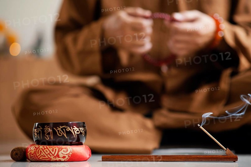 Front view defocused man meditating with beads singing bowl