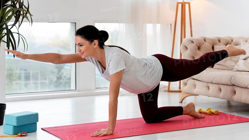 Side view pregnant woman doing yoga home