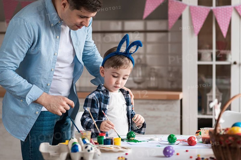 Father teaching little boy how paint eggs easter