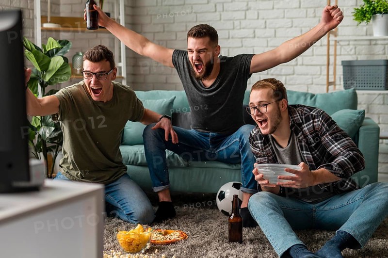Front view cheerful male friends watching sports tv together while having snacks beer