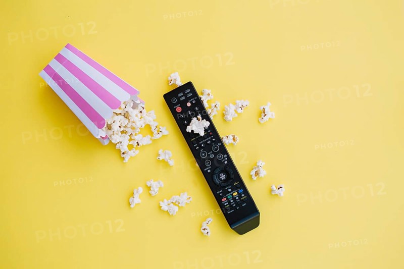 Tv remote control near spilled popcorn