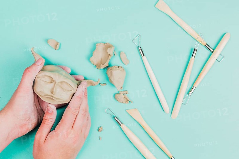 Close up sculptor artist creating sculpture face with clay colored background