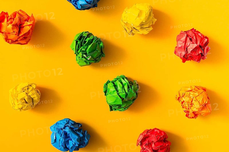 Colorful crumpled paper ball yellow background