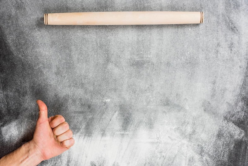 Flour background with rolling pin hands making ok sign