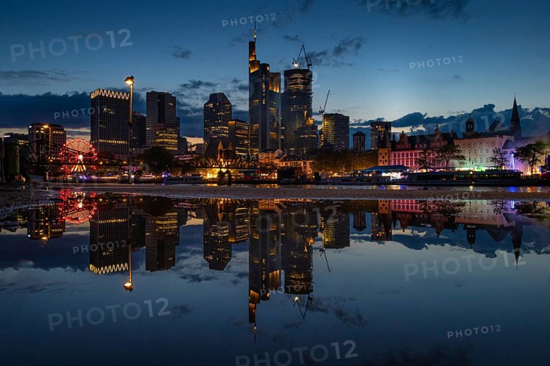 The colourful lights of the Mainfest are reflected in a puddle. The Mainfest on the Mainkai