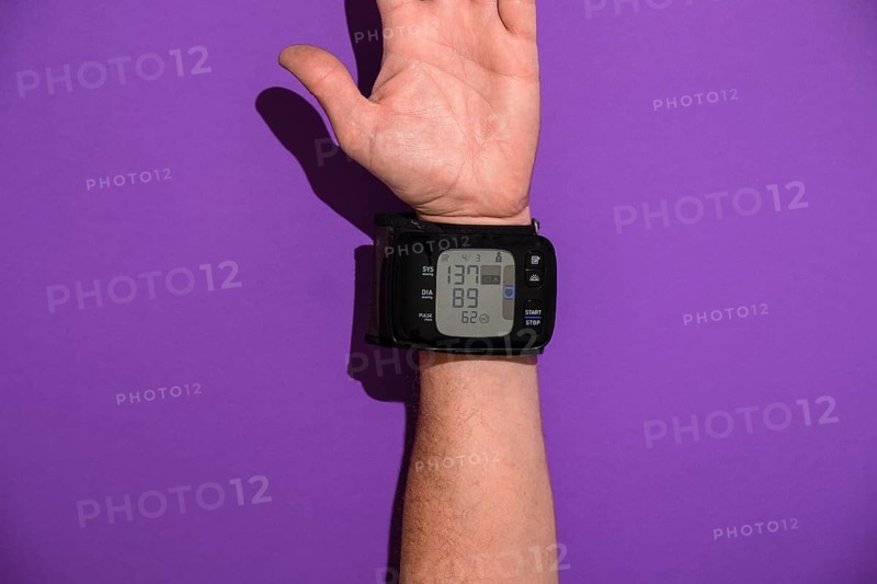 Blood pressure monitor on a man's trading joint against a violet background