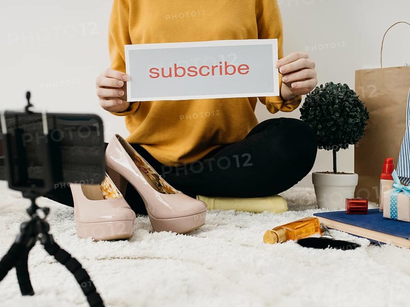 Female fashion blogger streaming home with smartphone subscribe word