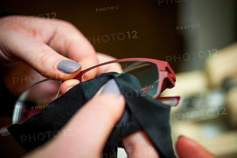 A woman cleans a pair of glasses