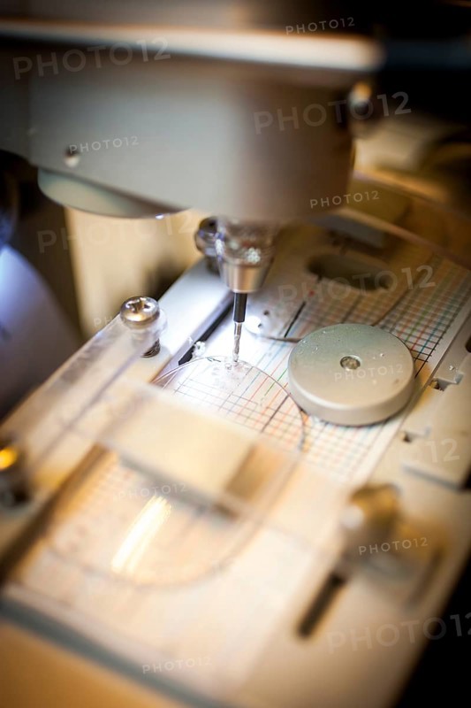 An optician drills a hole in a lens for the temple of a pair of glasses