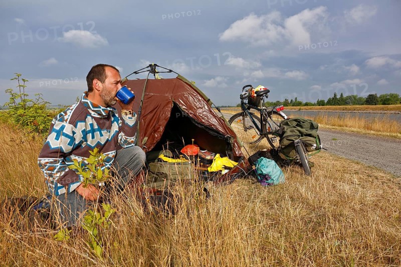 Cycle tourist drinking a coffee in front of his tent
