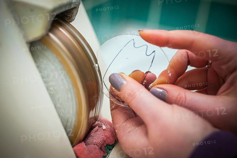A woman grinds a lens at an optician's shop