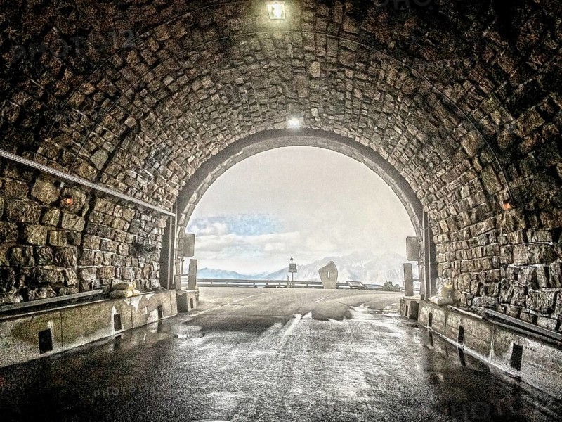 Photo with reduced dynamic saturation HDR of mountain pass alpine mountain road alpine road pass road pass view from tunnel Hochtor of Grossglockner High Alpine Road Grossglockner High Alpine Road in alpine high mountain massif of Grossglockner Massif