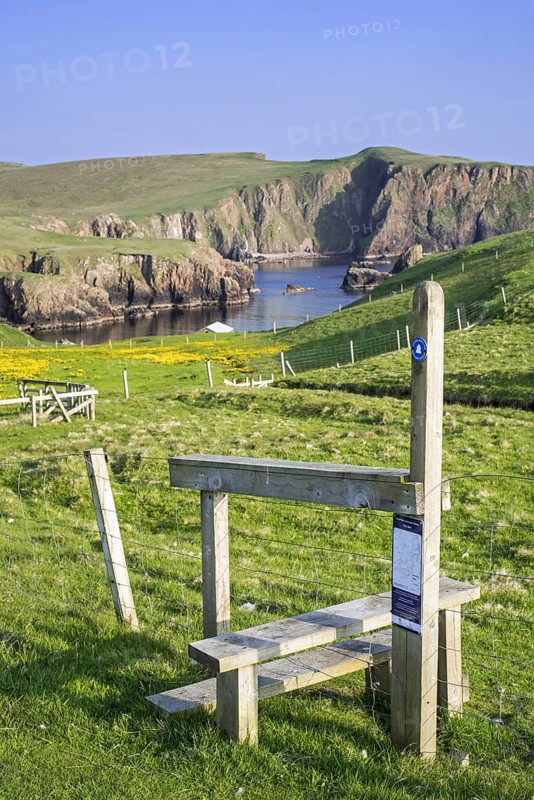Wooden stile crossing on fence along the spectacular coastline with sea cliffs and stacks at Westerwick
