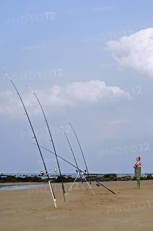 Sea angler with many fishing rods fishing from beach along the North Sea coast