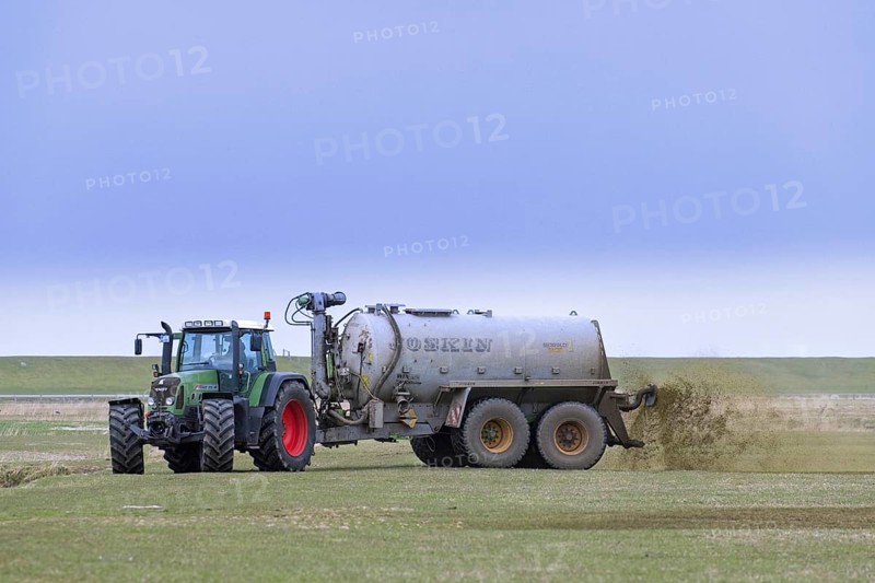 Farmer in Fendt 818 tractor with muck spreader distributing