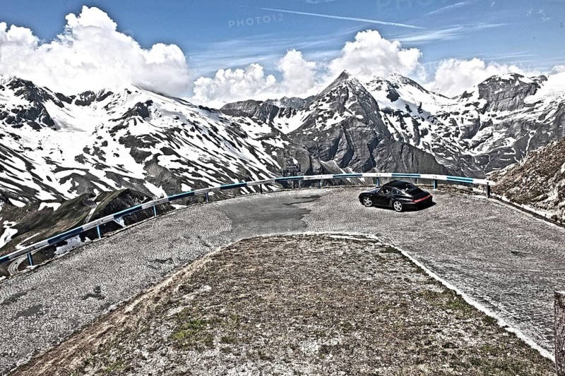Photo with reduced dynamic range saturation HDR of view of Porsche 911 993 driving into hairpin bend 5 of historic old Grossglockner High Alpine Road Grossglockner-Hochalpenstrasse with cobblestones mountain pass alpine mountain road alpine pass road pass above above tree line