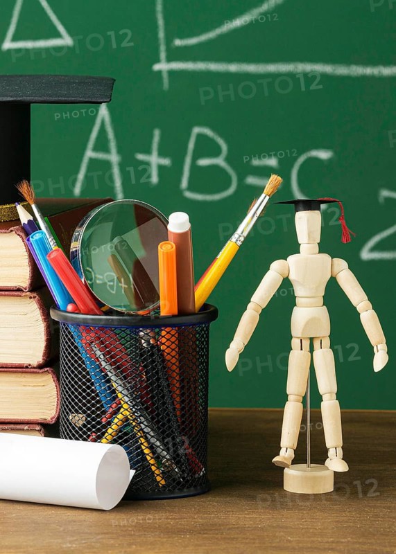 Front view wooden figurine with academic cap books
