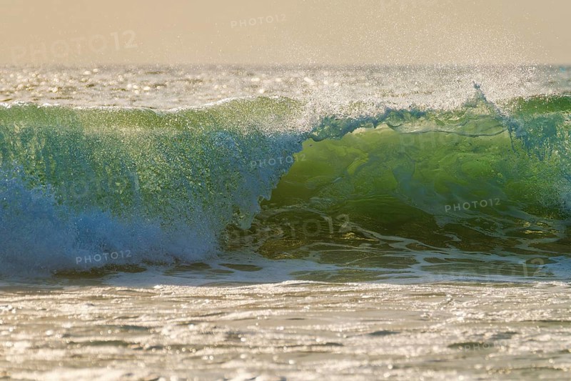 Breaking ocean wave on sunset backlit with sun. Fonte da Telha
