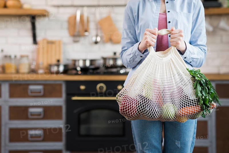 Adult woman holding reusable bag with organic vegetables