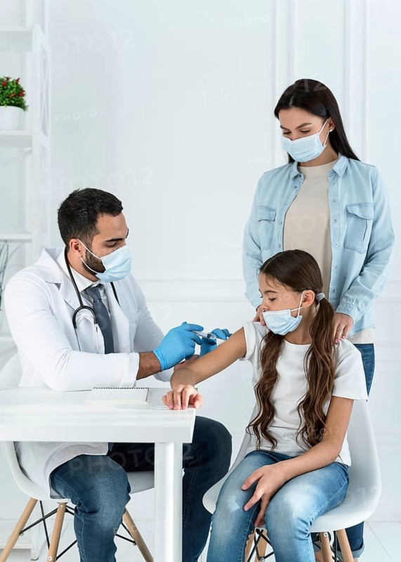Doctor vaccinating little girl that s supported by her mother