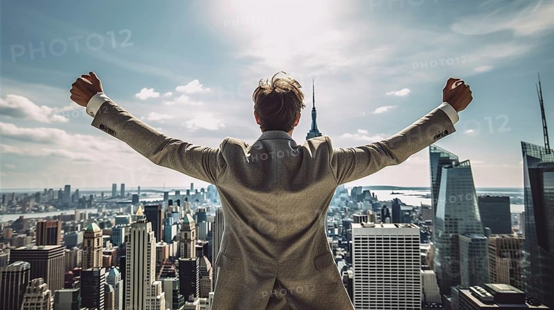 Excited businessman celebrates with his fists in the air with the city in the background