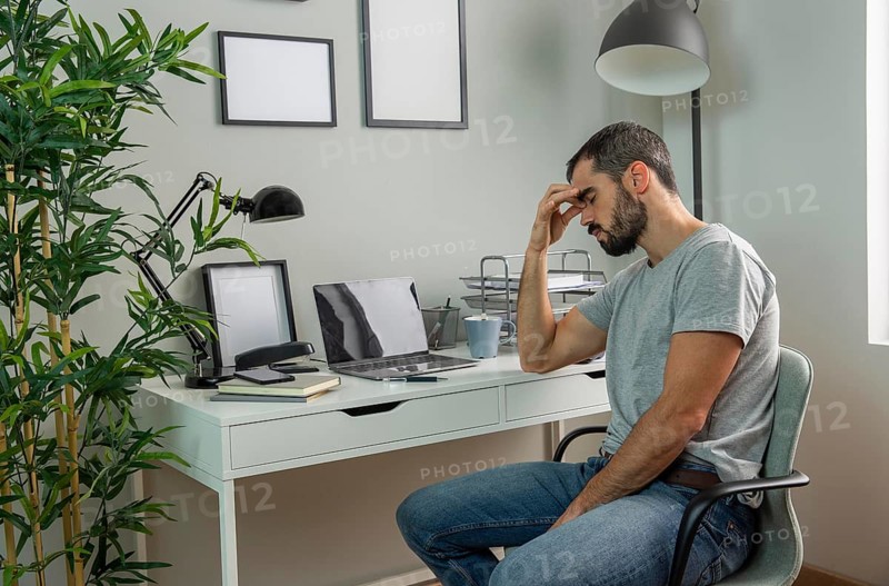 Tired man sitting his home desk