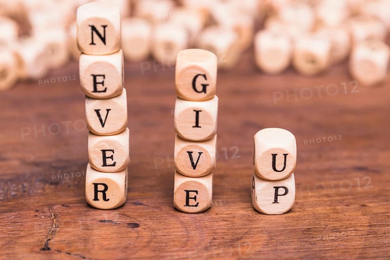 Stacked wooden blocks with word never give up wooden desk
