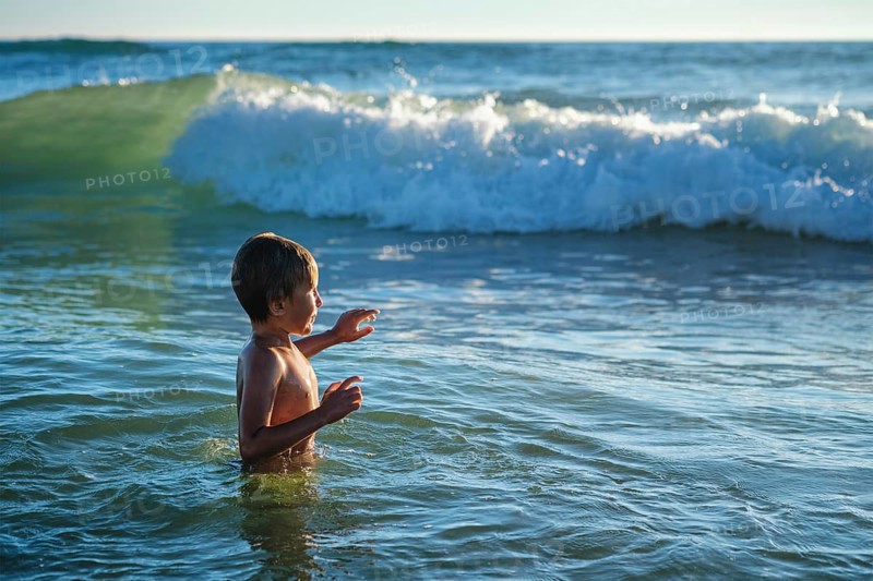 Boy has fun enjoys jumps dives in ocean sea waves of Atlantic Ocean. Fonta da Telha beach