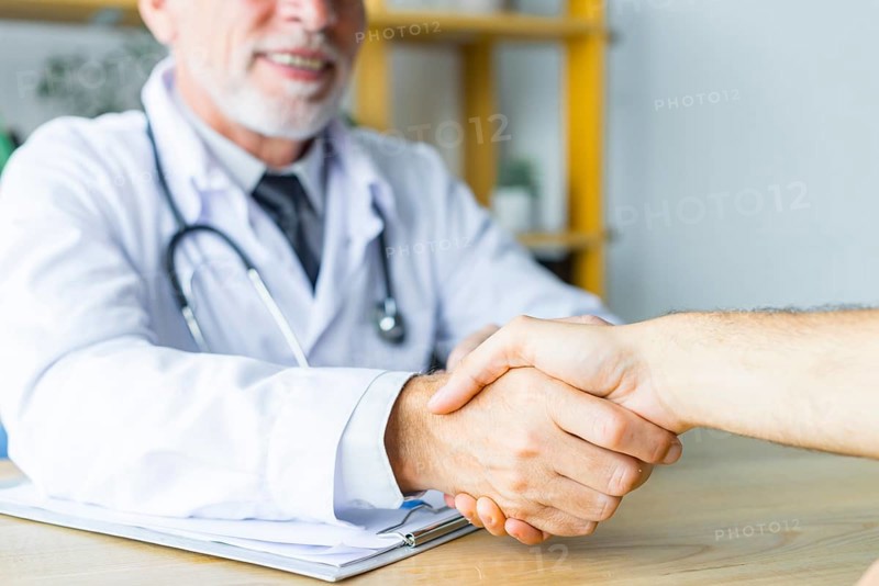 Smiling doctor shaking hand patient