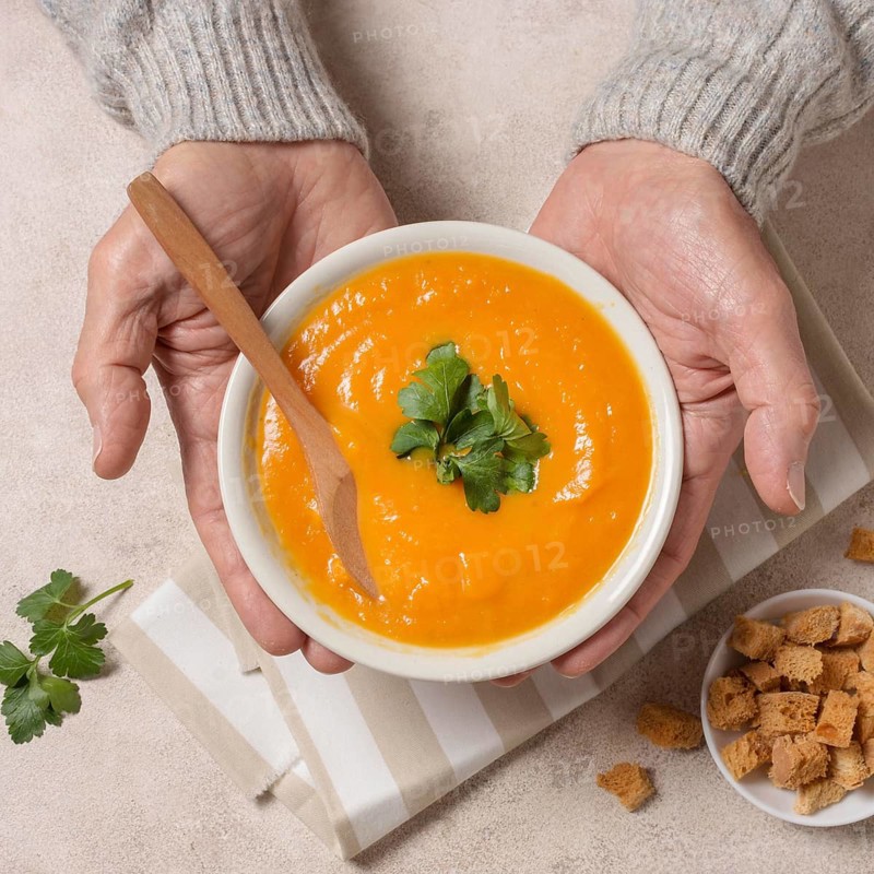 Close up hands holding cream soup bowl