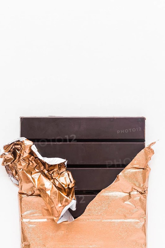 Delicious chocolate bar wrapped golden foil white background