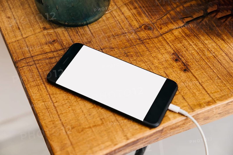 Smartphone with blank white screen wooden desk