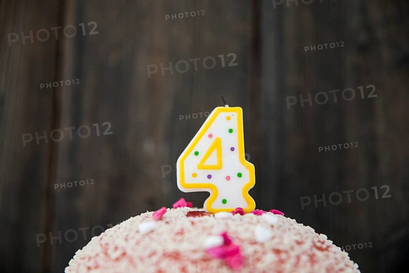 Number 4 candle birthday cake against blue wooden background
