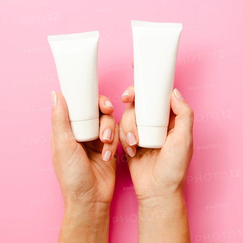 Close up hands holding cream bottles