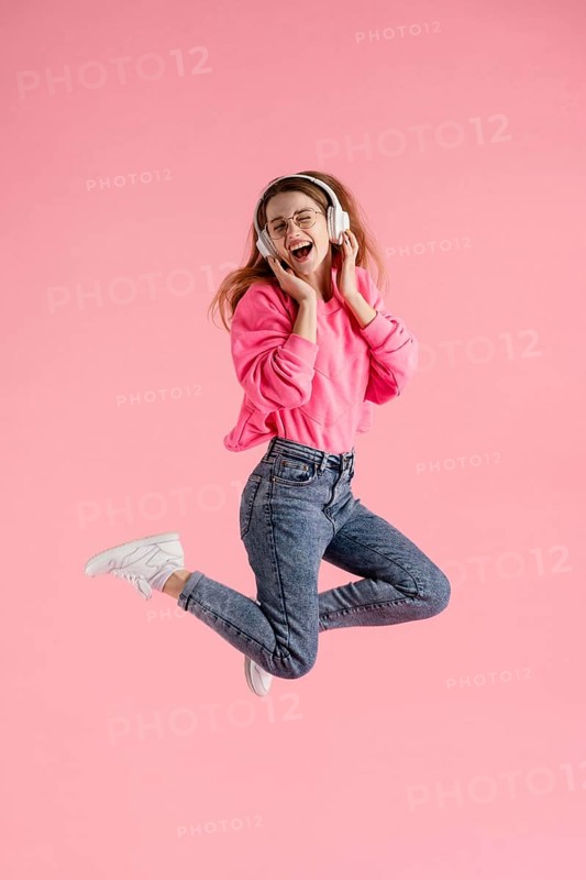 Portrait happy woman jumping listening music