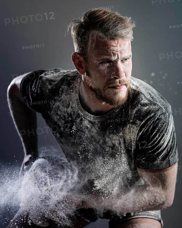 Front view athletic male rugby player holding ball with dust
