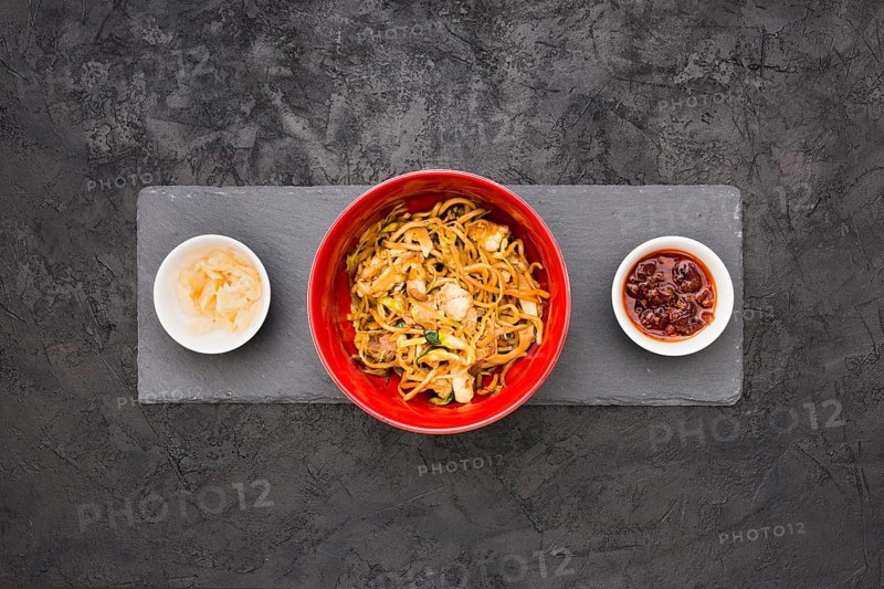 Overhead view delicious noodles bowl with sauce marinated ginger black slate stone