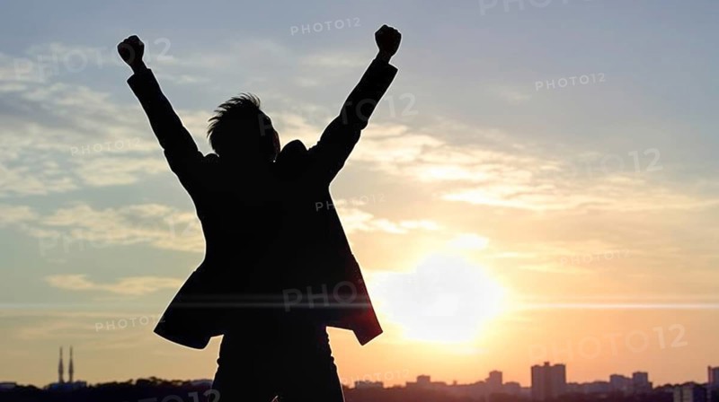 Excited businessman celebrates with his fists in the air with the city in the background