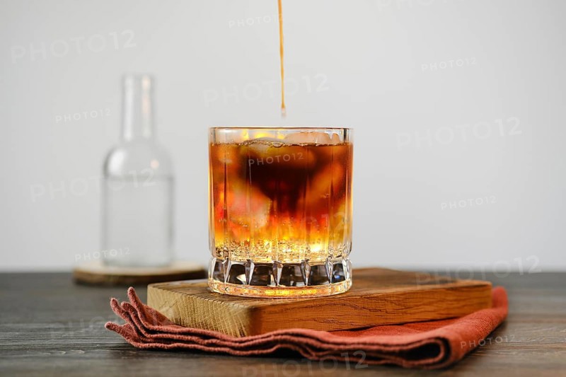 Pouring espresso in glass with tonic and ice cubes